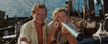 Movie still from “Swiss Family Robinson” (1960), directed by Ken Annakin – Two men are standing next to each other; Close Up shot, High angle