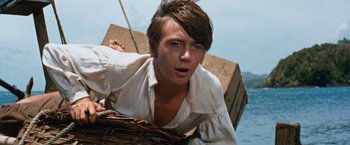 Movie still from “Swiss Family Robinson” (1960), directed by Ken Annakin – A young man in a white shirt is on a boat; Close Up shot, Low angle