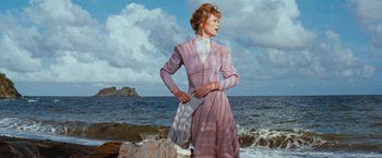 Movie still from “Swiss Family Robinson” (1960), directed by Ken Annakin – A woman standing on the beach in a pink dress; Medium shot, Low angle