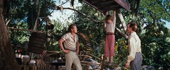 Movie still from “Swiss Family Robinson” (1960), directed by Ken Annakin – A man standing next to a boy hanging from a wooden structure; Medium shot, Low angle