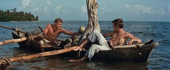 Movie still from “Swiss Family Robinson” (1960), directed by Ken Annakin – Two young men are sitting on a boat in the water; Wide shot, Low angle