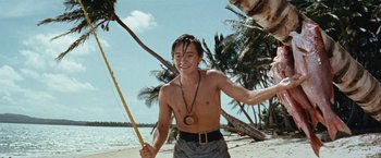 Movie still from “Swiss Family Robinson” (1960), directed by Ken Annakin – A man holding a pole on the beach; Medium shot, Low angle