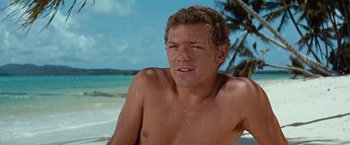 Movie still from “Swiss Family Robinson” (1960), directed by Ken Annakin – A man sitting on the beach with his eyes closed; Close Up shot, Low angle