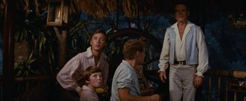 Movie still from “Swiss Family Robinson” (1960), directed by Ken Annakin – A group of people sitting in front of a tree; Medium shot, Low angle