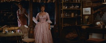 Movie still from “Swiss Family Robinson” (1960), directed by Ken Annakin – A woman in a pink dress standing in front of a mirror; Medium shot, Low angle