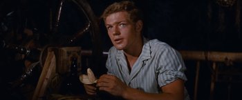 Movie still from “Swiss Family Robinson” (1960), directed by Ken Annakin – A man sitting at a table holding a piece of food; Close Up shot, High angle
