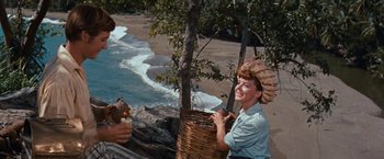 Movie still from “Swiss Family Robinson” (1960), directed by Ken Annakin – A woman is holding a basket on the beach; Medium shot, High angle
