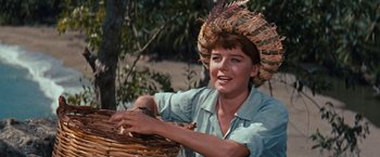 Movie still from “Swiss Family Robinson” (1960), directed by Ken Annakin – A woman wearing a hat and holding a basket of food; Close Up shot, Low angle
