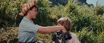Movie still from “Swiss Family Robinson” (1960), directed by Ken Annakin – A man and a boy are holding binoculars in a field; Close Up shot, Over the shoulder angle