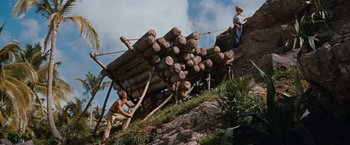 Movie still from “Swiss Family Robinson” (1960), directed by Ken Annakin – Two men working on a pile of logs on top of a hill; Wide shot, Low angle