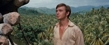 Movie still from “Swiss Family Robinson” (1960), directed by Ken Annakin – A man standing in front of a palm tree filled forest; Close Up shot, Low angle
