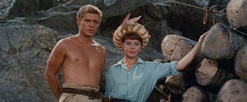 Movie still from “Swiss Family Robinson” (1960), directed by Ken Annakin – A man standing next to a woman wearing a headpiece; Medium shot, Low angle
