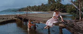 Movie still from “Swiss Family Robinson” (1960), directed by Ken Annakin – A man and a woman sitting on a pier; Wide shot, High angle