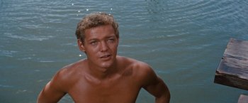 Movie still from “Swiss Family Robinson” (1960), directed by Ken Annakin – A shirtless man standing in the water near the shore; Close Up shot, High angle