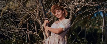 Movie still from “Swiss Family Robinson” (1960), directed by Ken Annakin – A young woman holding a rifle in a forest; Medium shot, Low angle
