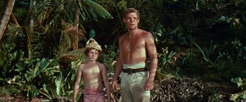 Movie still from “Swiss Family Robinson” (1960), directed by Ken Annakin – A man standing next to a young boy in the woods; Medium shot, Low angle