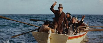 Movie still from “Swiss Family Robinson” (1960), directed by Ken Annakin – A man in a hat waves from a small boat; Wide shot, Low angle