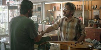 Movie still from “Sword of Trust” (2019), directed by Lynn Shelton – Two men shaking hands in an office setting; Medium shot, Over the shoulder angle