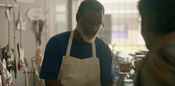 Movie still from “Sword of Trust” (2019), directed by Lynn Shelton – An older man wearing an apron is looking down; Medium shot, Over the shoulder angle