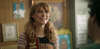 Movie still from “Sword of Trust” (2019), directed by Lynn Shelton – A woman with long red hair smiling at the camera; Close Up shot, Over the shoulder angle