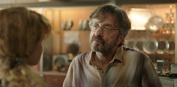 Movie still from “Sword of Trust” (2019), directed by Lynn Shelton – A man with a beard wearing glasses looking at the camera; Close Up shot, Over the shoulder angle