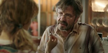 Movie still from “Sword of Trust” (2019), directed by Lynn Shelton – A man with a beard and glasses is holding a lipstick; Close Up shot, Over the shoulder angle