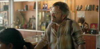 Movie still from “Sword of Trust” (2019), directed by Lynn Shelton – An older man wearing glasses and a plaid shirt; Close Up shot, Over the shoulder angle