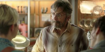 Movie still from “Sword of Trust” (2019), directed by Lynn Shelton – An older man wearing glasses and a button down shirt; Close Up shot, Over the shoulder angle