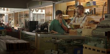 Movie still from “Sword of Trust” (2019), directed by Lynn Shelton – Two men are standing at a counter in a bakery; Medium shot, Over the shoulder angle