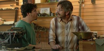 Movie still from “Sword of Trust” (2019), directed by Lynn Shelton – A man and a boy talking to each other in front of a counter; Medium shot, Over the shoulder angle
