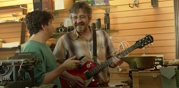 Movie still from “Sword of Trust” (2019), directed by Lynn Shelton – A man holding an electric guitar while another man holds an electric guitar; Medium shot, Over the shoulder angle