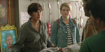 Movie still from “Sword of Trust” (2019), directed by Lynn Shelton – Two women standing next to each other in front of guitars; Medium shot, Over the shoulder angle
