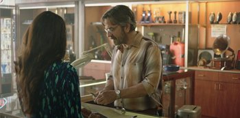 Movie still from “Sword of Trust” (2019), directed by Lynn Shelton – A man is signing a document for a woman; Medium shot, Over the shoulder angle