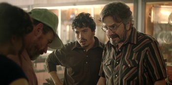 Movie still from “Sword of Trust” (2019), directed by Lynn Shelton – A group of men standing next to each other in a room; Medium shot, Over the shoulder angle