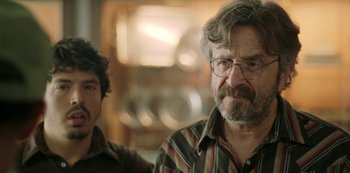 Movie still from “Sword of Trust” (2019), directed by Lynn Shelton – A man with a beard and glasses is looking at the camera; Close Up shot, Over the shoulder angle