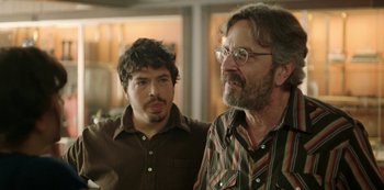 Movie still from “Sword of Trust” (2019), directed by Lynn Shelton – Two men standing next to each other in front of a window; Close Up shot, Over the shoulder angle