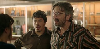 Movie still from “Sword of Trust” (2019), directed by Lynn Shelton – Two men standing next to each other in front of a window; Medium shot, Over the shoulder angle