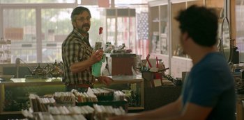 Movie still from “Sword of Trust” (2019), directed by Lynn Shelton – A man standing at a counter in a store; Medium shot, Over the shoulder angle