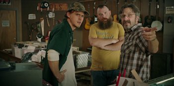 Movie still from “Sword of Trust” (2019), directed by Lynn Shelton – A group of men standing next to each other in a room; Medium shot, Over the shoulder angle