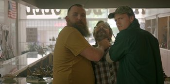 Movie still from “Sword of Trust” (2019), directed by Lynn Shelton – A man with a long beard getting his beard shaved by two other men; Medium shot, Over the shoulder angle
