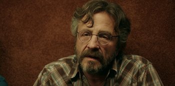 Movie still from “Sword of Trust” (2019), directed by Lynn Shelton – A person wearing glasses and a plaid shirt; Close Up shot, Over the shoulder angle