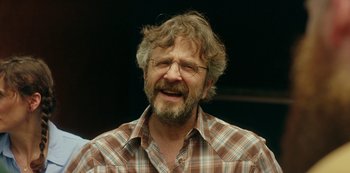Movie still from “Sword of Trust” (2019), directed by Lynn Shelton – An older man with a beard and glasses is smiling for the camera; Close Up shot, Over the shoulder angle