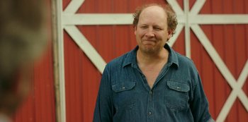 Movie still from “Sword of Trust” (2019), directed by Lynn Shelton – A man standing in front of a red barn; Close Up shot, Over the shoulder angle