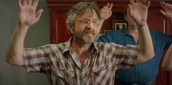 Movie still from “Sword of Trust” (2019), directed by Lynn Shelton – A man in a plaid shirt is raising his arms; Medium shot, Over the shoulder angle