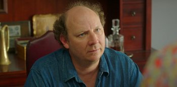 Movie still from “Sword of Trust” (2019), directed by Lynn Shelton – A man with a bald head is sitting in a room; Close Up shot, Over the shoulder angle