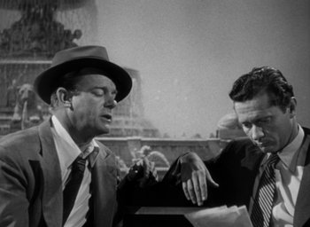 Movie still from “T-Men” (1947), directed by Anthony Mann – A man in a suit and a hat talking to another man in a suit and a hat; Medium shot, Low angle