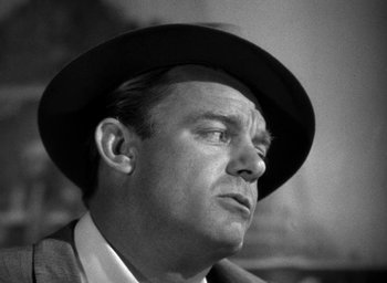 Movie still from “T-Men” (1947), directed by Anthony Mann – A man wearing a suit and a hat looking to his left; Close Up shot, Low angle