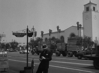 Movie still from “T-Men” (1947), directed by Anthony Mann – A black and white photo of a man standing on the side of the road; Extreme Wide shot, Low angle