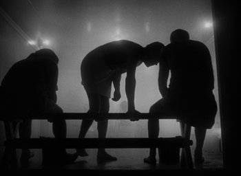 Movie still from “T-Men” (1947), directed by Anthony Mann – A group of men standing on top of a wooden bench; Wide shot, Low angle