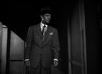 Movie still from “T-Men” (1947), directed by Anthony Mann – A black and white photo of a man in a suit and hat; Medium shot, Low angle